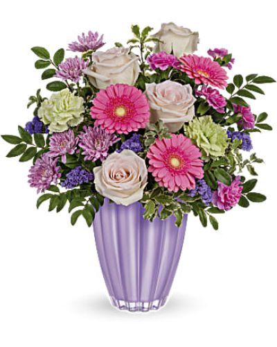 Put a spring in their step with this playful bouquet of pink and purple blooms, presented to perfection in a pastel purple vase of European glass with radiant metallic finish.

Blush roses, miniature pink gerberas, green carnations, miniature hot pink carnations and lavender cushion spray chrysanthemums are arranged with huckleberry and pitta negra.